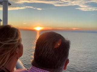 Two people looking out over the sunset from a cruise ship